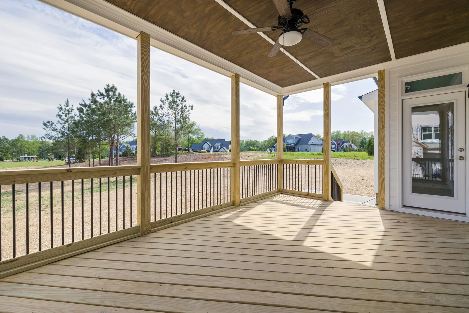 A new covered porch with a wood deck, railings and a ceiling fan